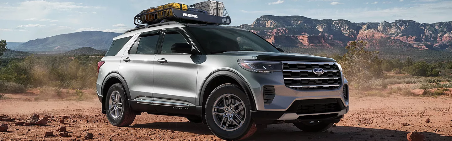 2026 Ford Explorer parked in front of desert mountains with a roof rack and gear on top