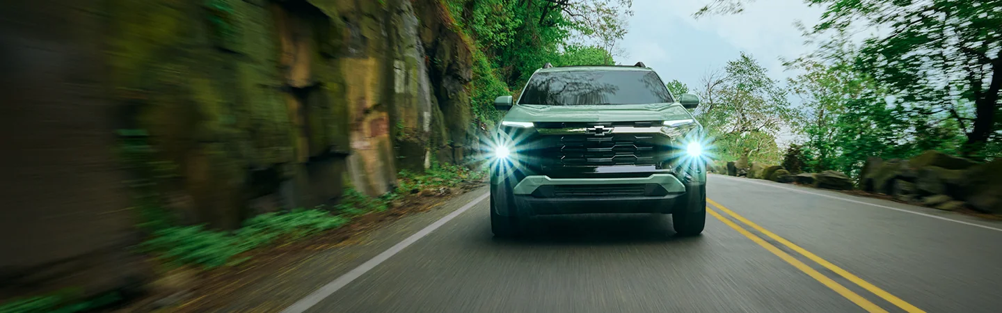 front view of a green 2026 Chevrolet Equinox LT with lights on