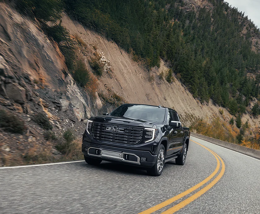 Front view of a black 2026 GMC Sierra 1500 driving on a mountian side road