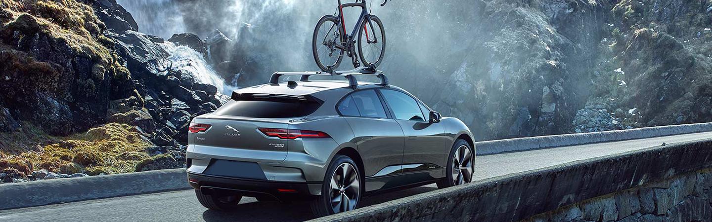 A 2022 Jaguar I-PACE driving next to a waterfall