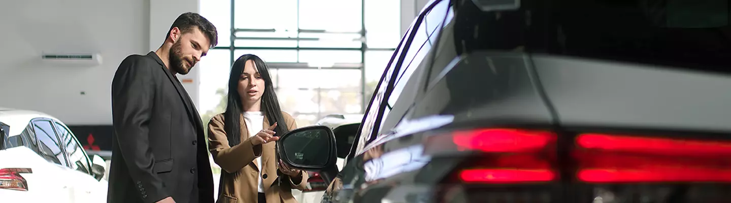 A couple inspects a car in a modern showroom