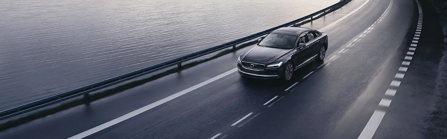 black 2025 Volvo S90 Plug-in Hybrid driving on highway