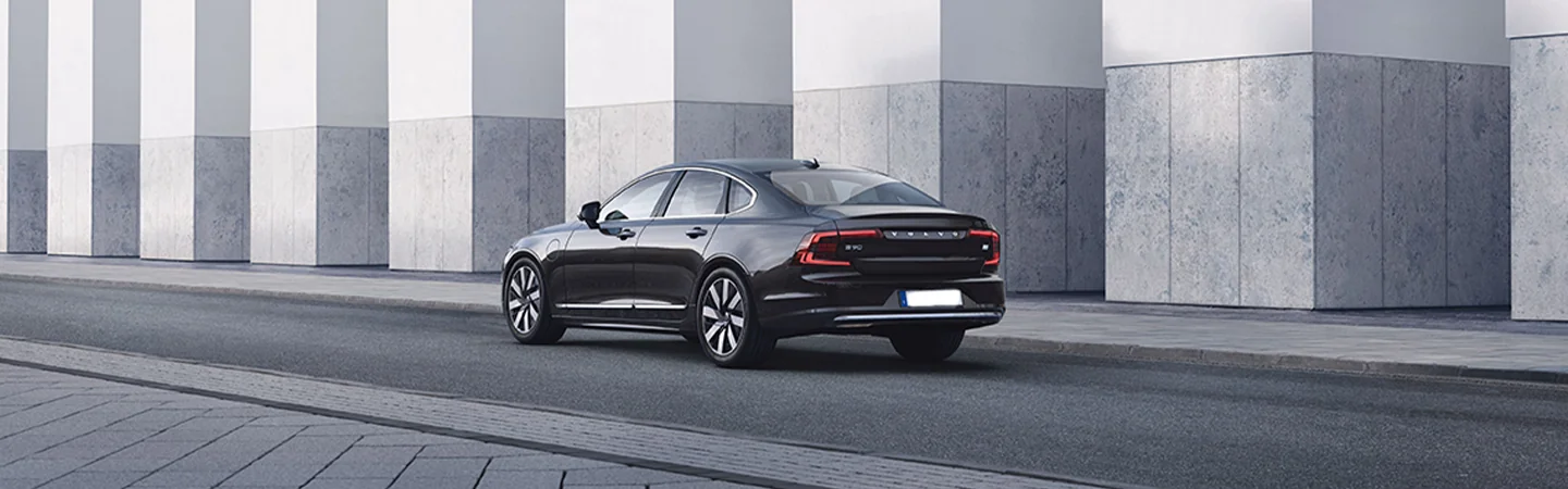 black 2025 Volvo S90 Plug-in Hybrid driving in a city
