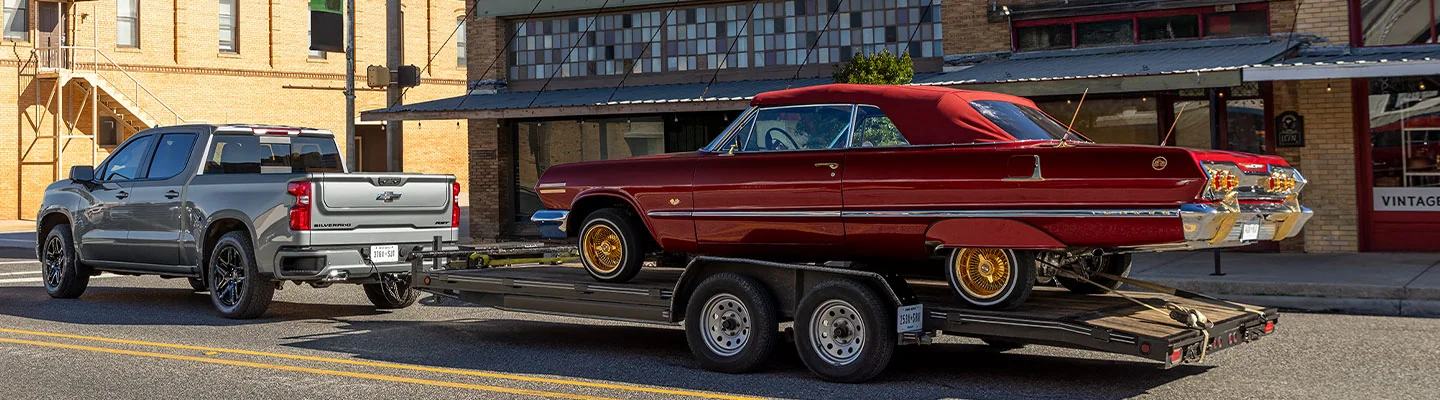 A gray 2025 Chevy Silverado towing a lowrider