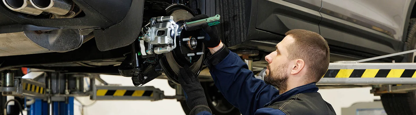 auto mechanic working on brakes on a car on lift