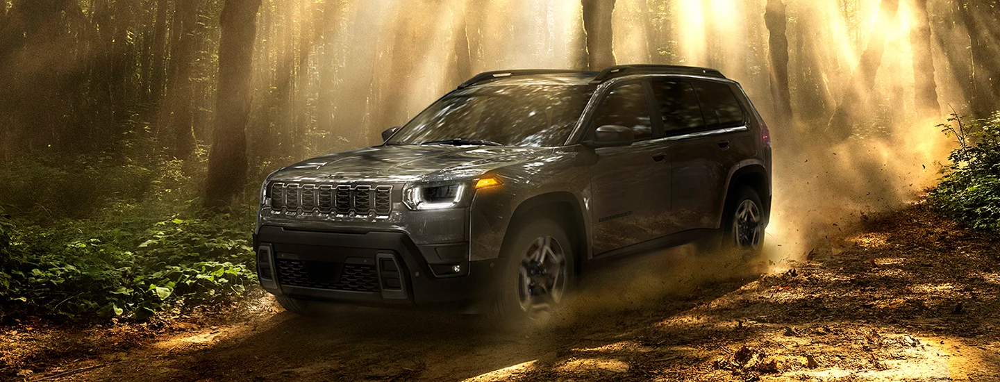 Front view of a gray 2026 Jeep Cherokee driving int he woods