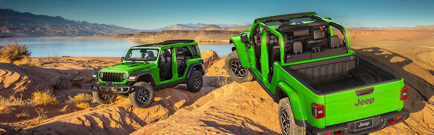 Two 2026 Jeep Wranglers parked on desert hills in front of a lake with mountains in the background
