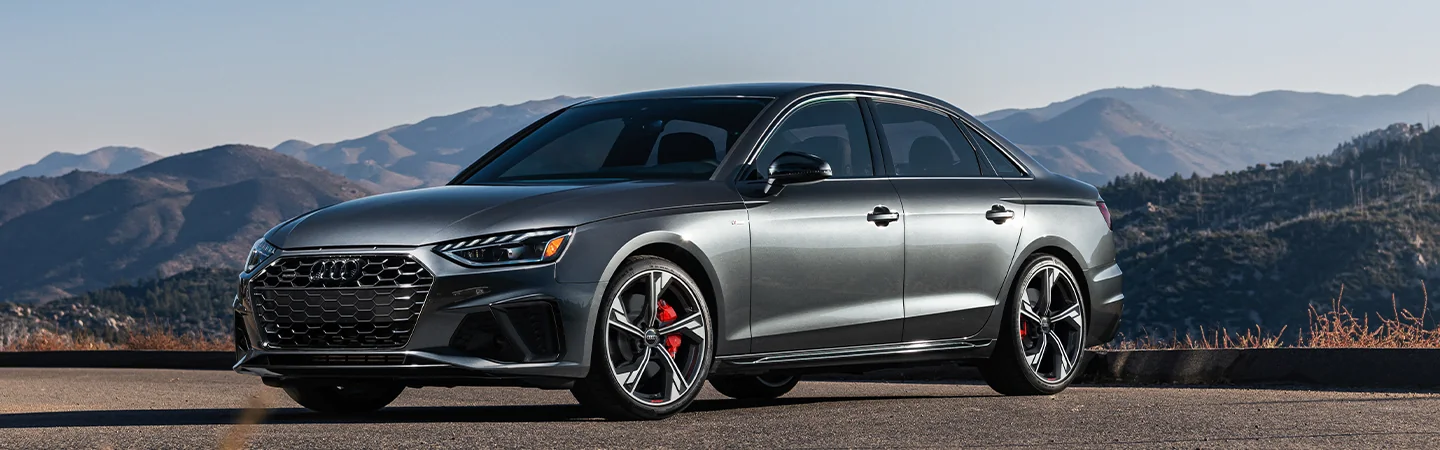 Front side view of a parked gray 2025 Audi A4 with mountains in the background