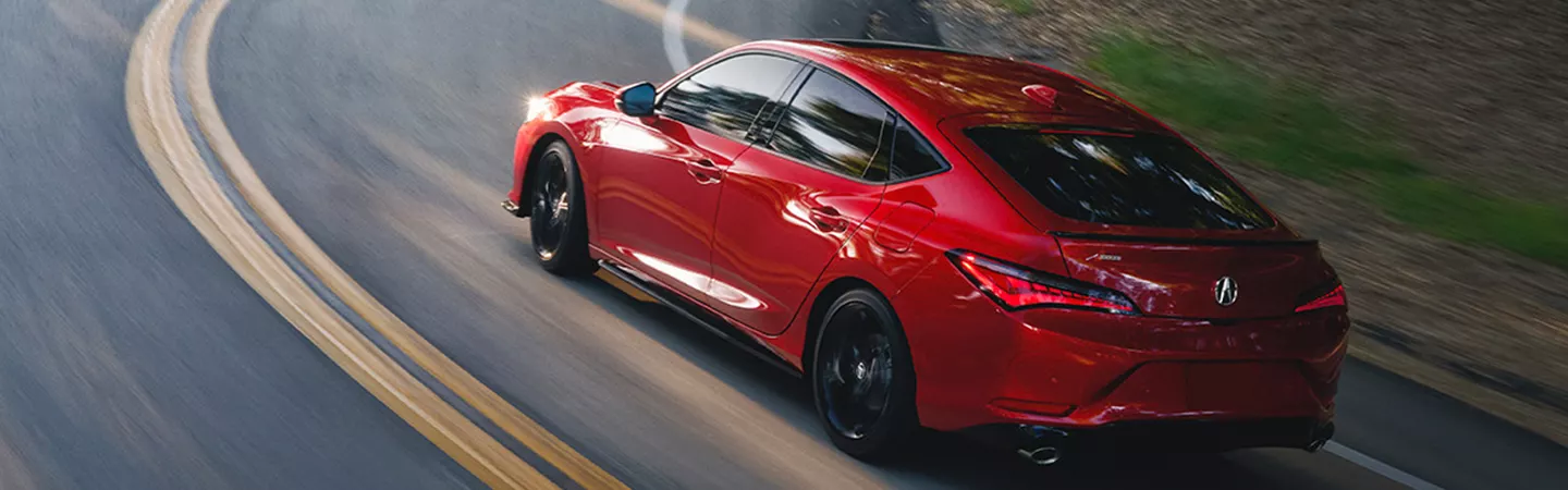 Rear view of the 2026 Acura Integra driving on a country road