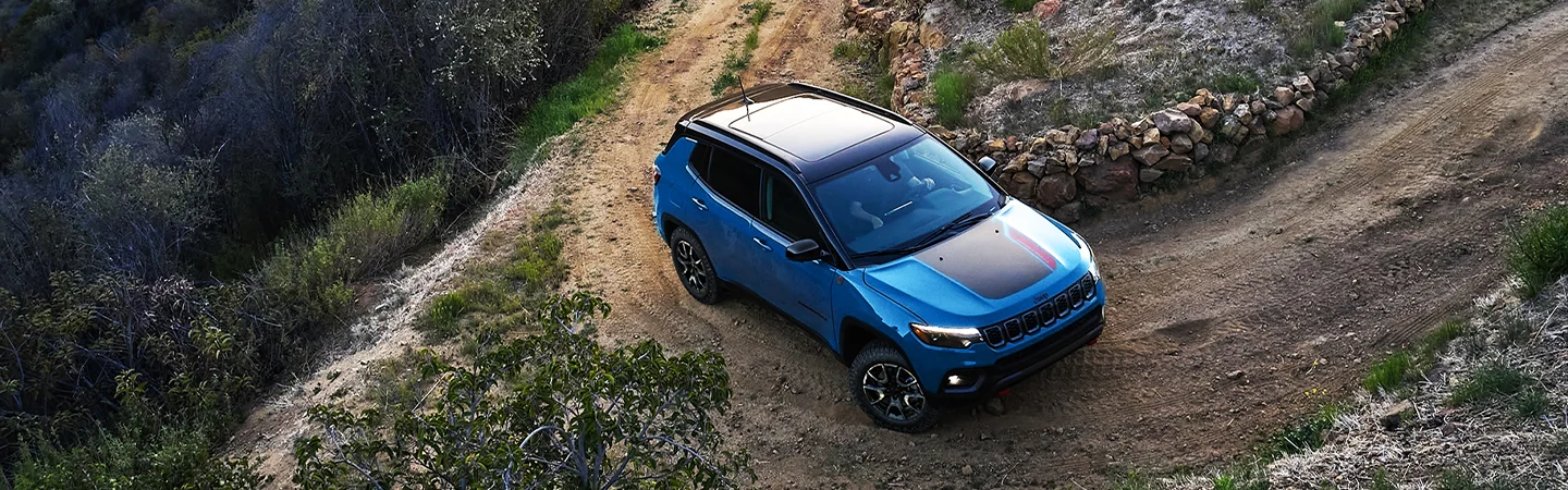 2026 Jeep Compass Limited taking a turn on a dirt road switchback
