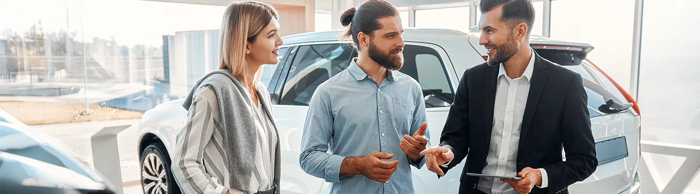 salesman talking with man and woman in the dealership