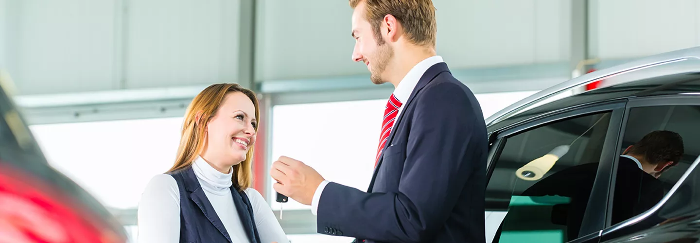 sales man giving the keys to the vehicle to a woman