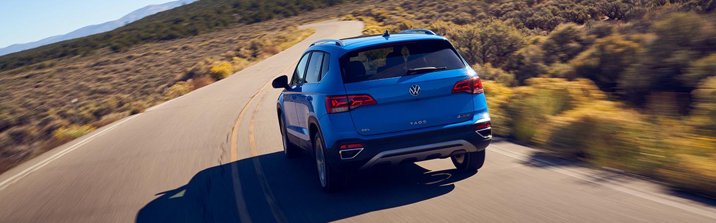 Back view of a blue 2022 Volkswagen Taos dring on the road