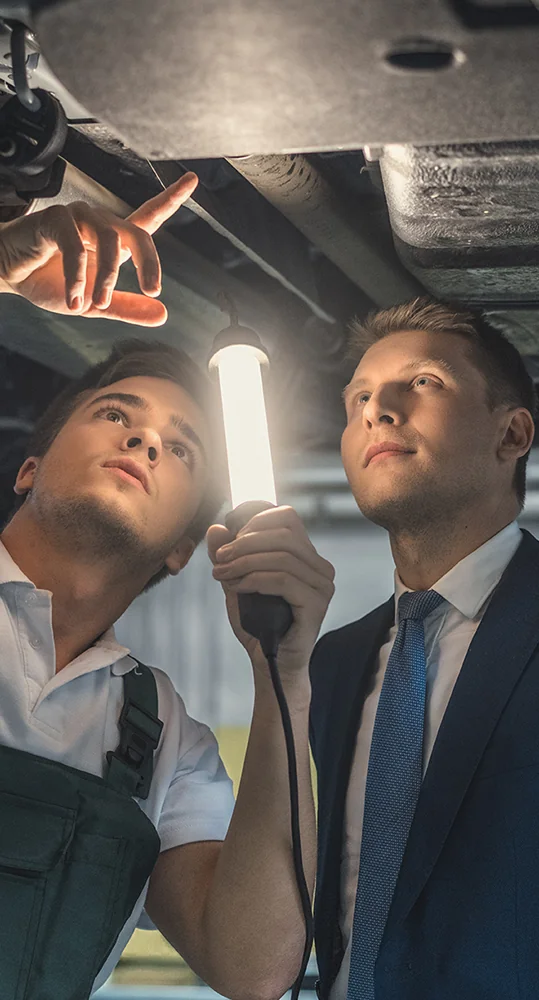 Service techs checking under a car