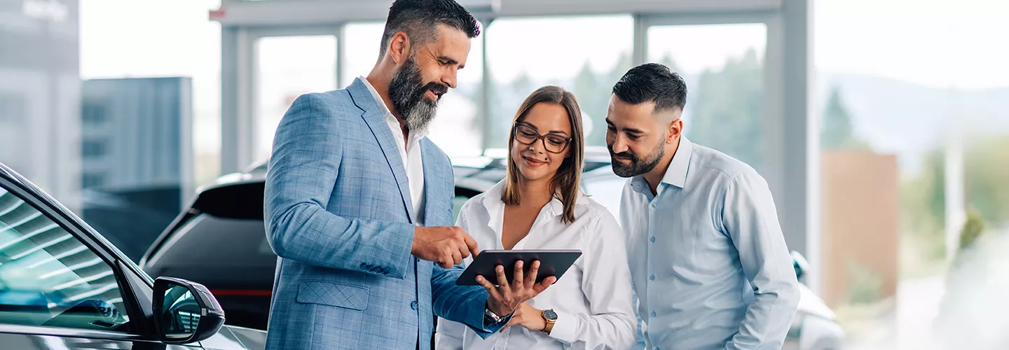 Car salesperson speaking with customers about a new vehicle