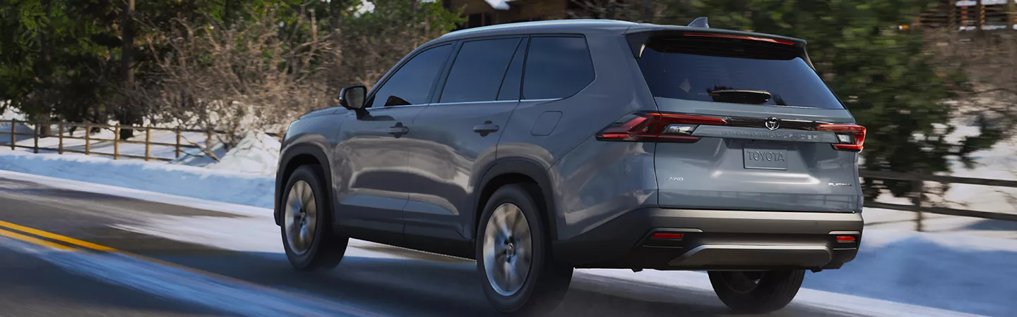 Rear view of the 2026 Toyota Grand Highlander driving on a snowy road