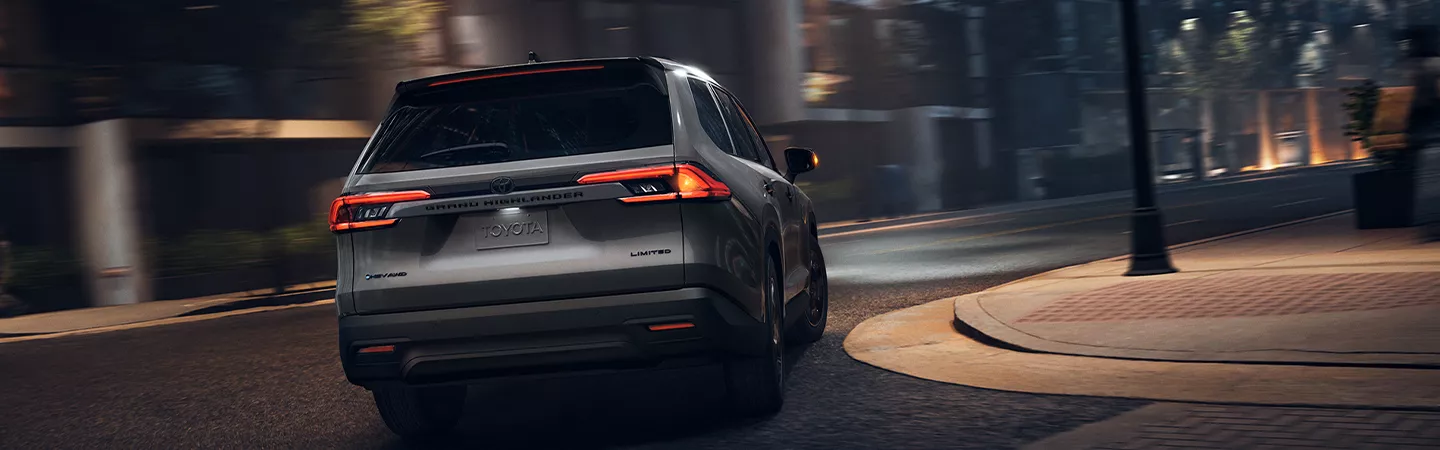 Rear view of the 2026 Toyota Grand Highlander driving through the city at night
