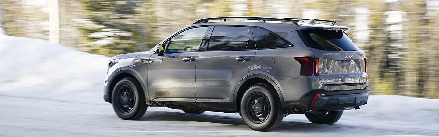 Side view of a gray 2025 Kia Sorento driving on a snowy road
