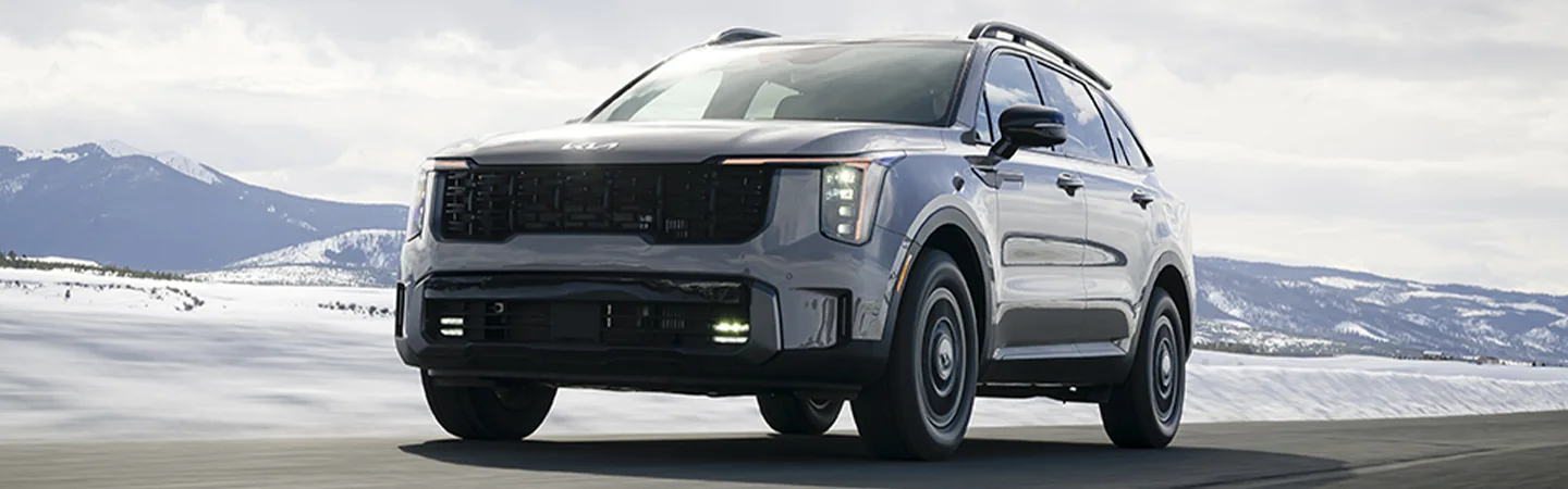 Front view of a gray 2025 Kia Sorento driving though a snowy mountain scape