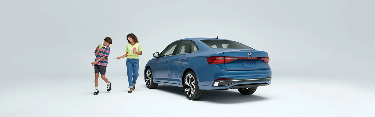 a blue Volkswagen Jetta with two kids playing around it