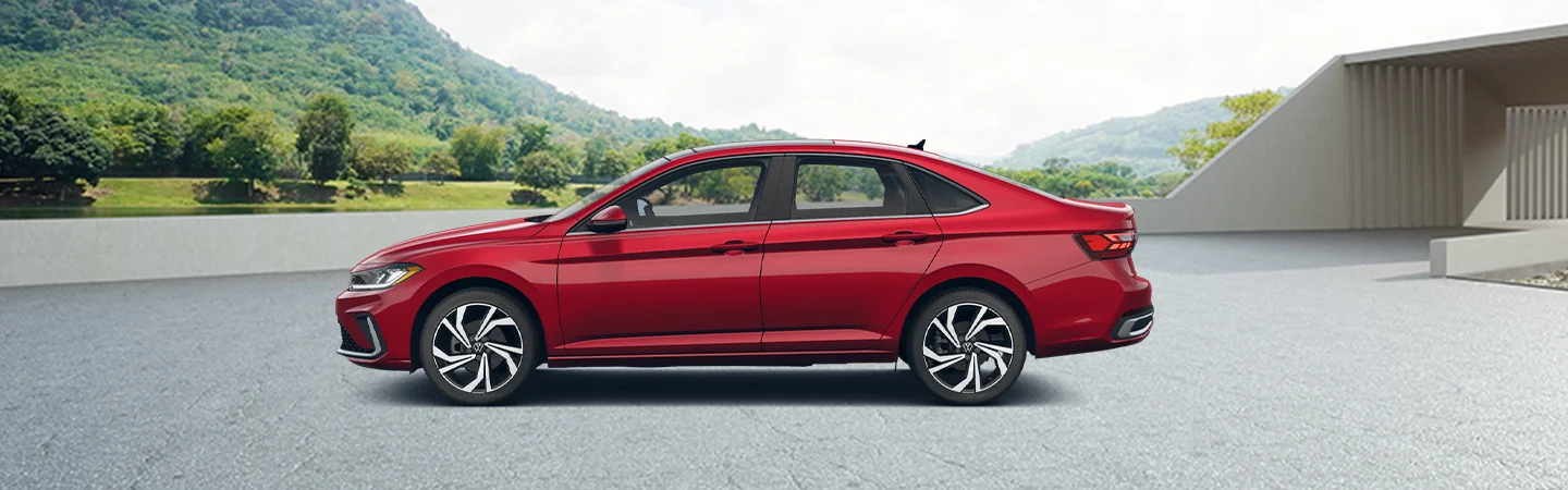 a driver side view of a red Volkswagen Jetta parked by modern house