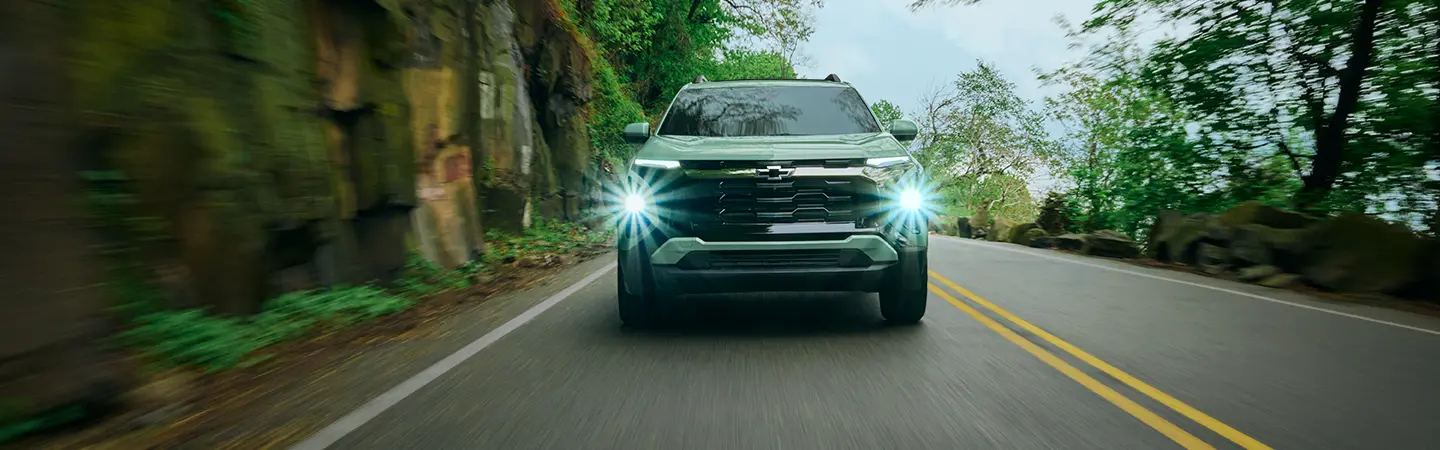 Red 2025 Chevrolet Trax driving though the woods