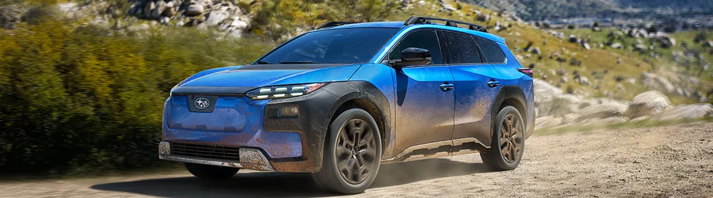 Front side view of a blue 2026 Subaru Trailseeker driving on a dirt road