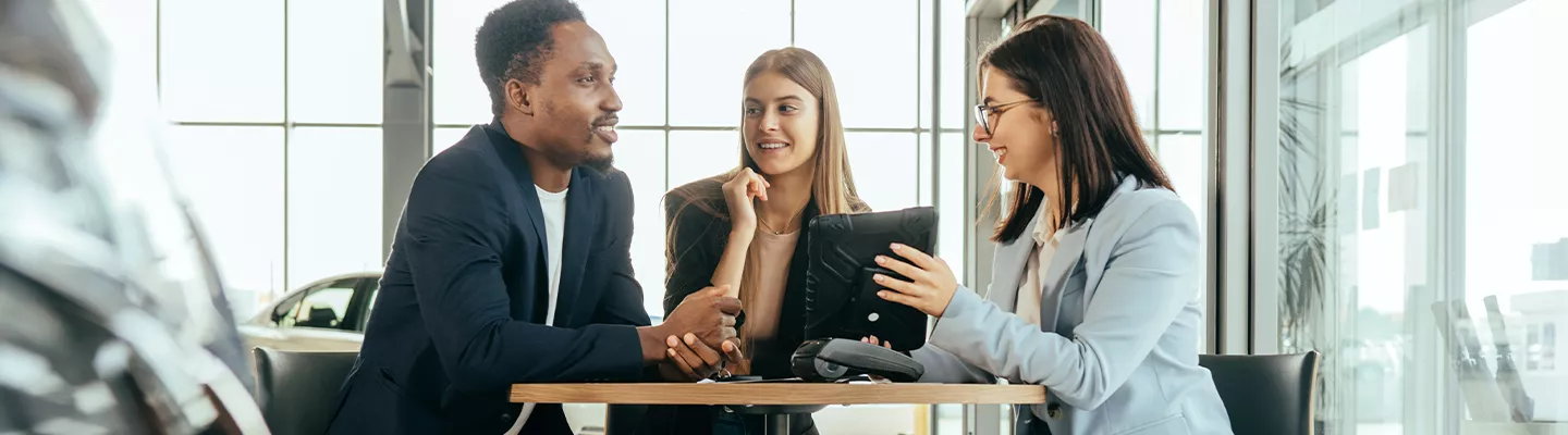 saleswoman showing man and woman information on a tablet