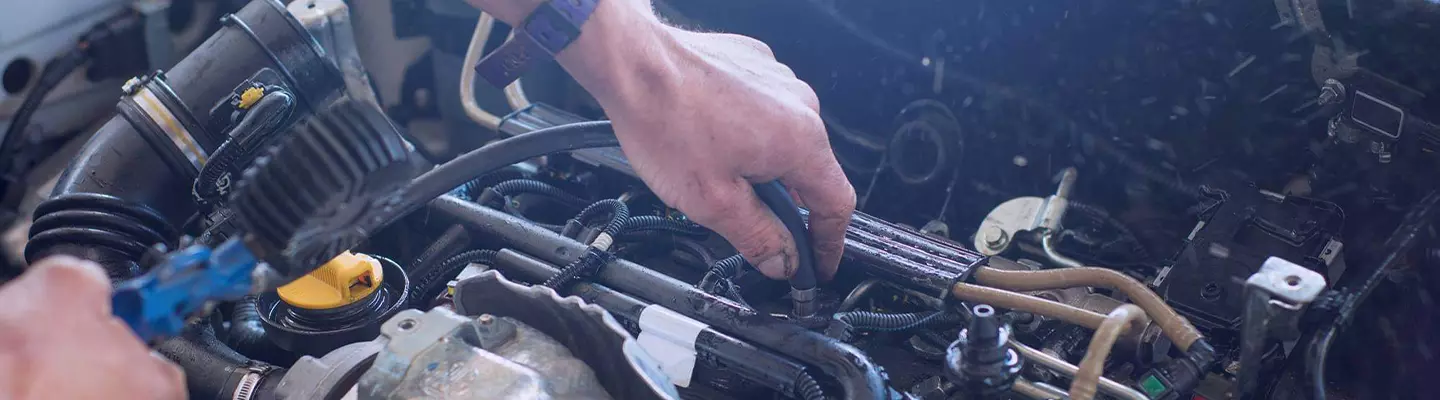 A person is focused on repairing a car engine, surrounded by tools and parts in a garage setting.  