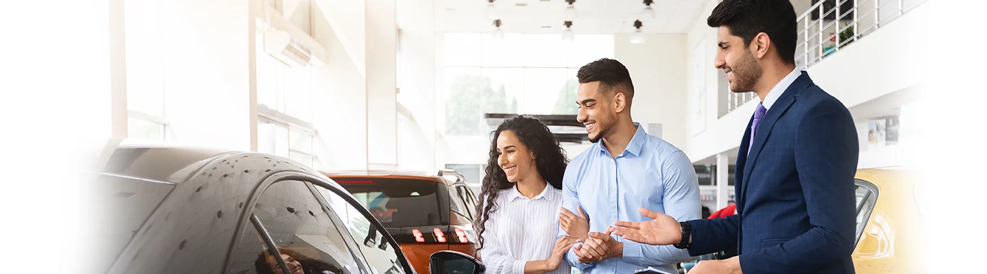 couple speaking with car salesman in showroom