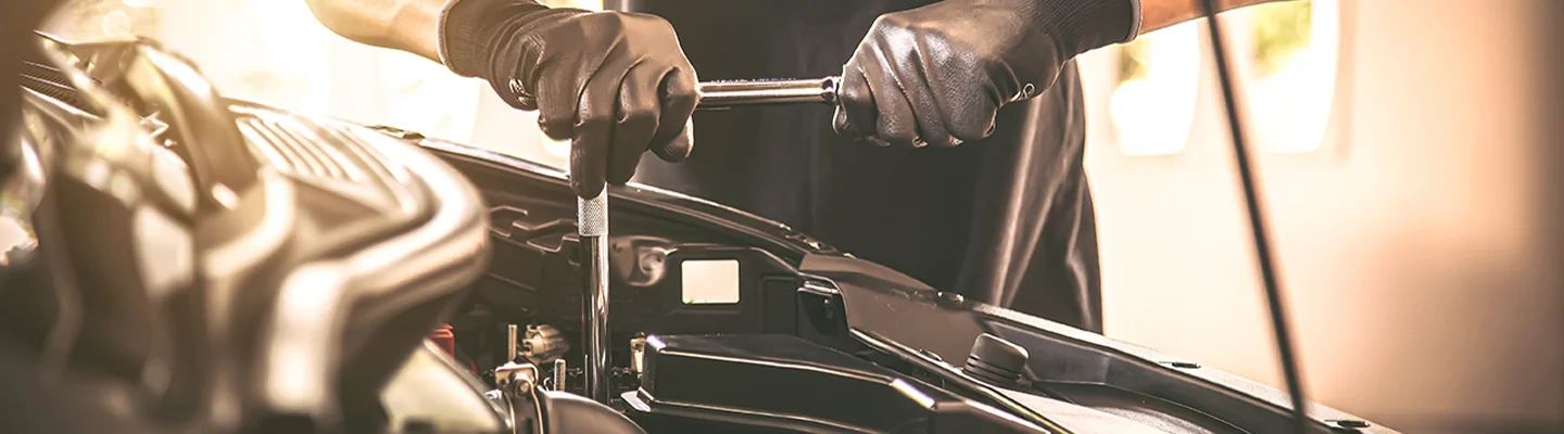 auto mechanic with tool working on engine