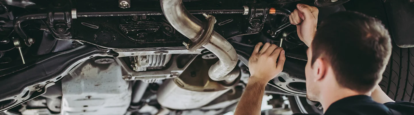 car mechanic working on car on a lift from underneath