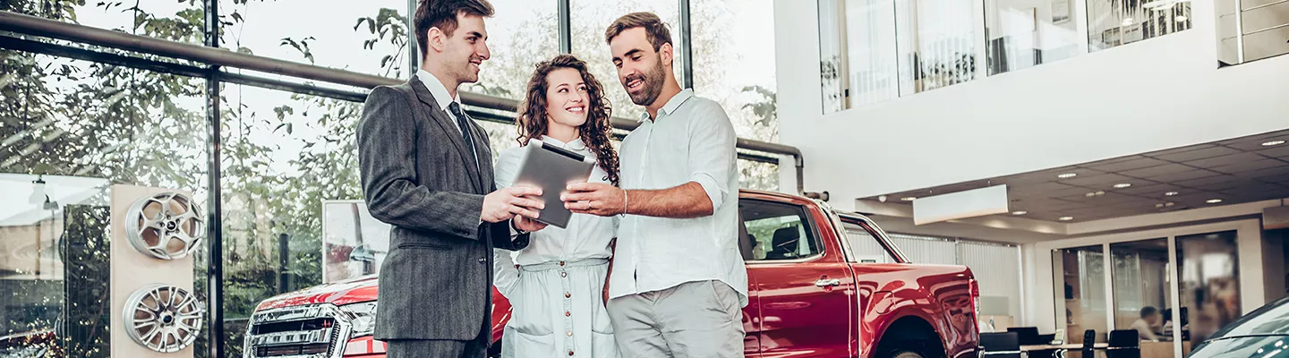 Car salesperson speaking with customers about a used Ford truck or SUV