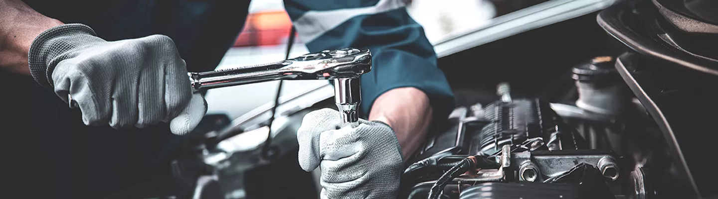 Maintenance technician working under the hood of a Chevrolet vehicle