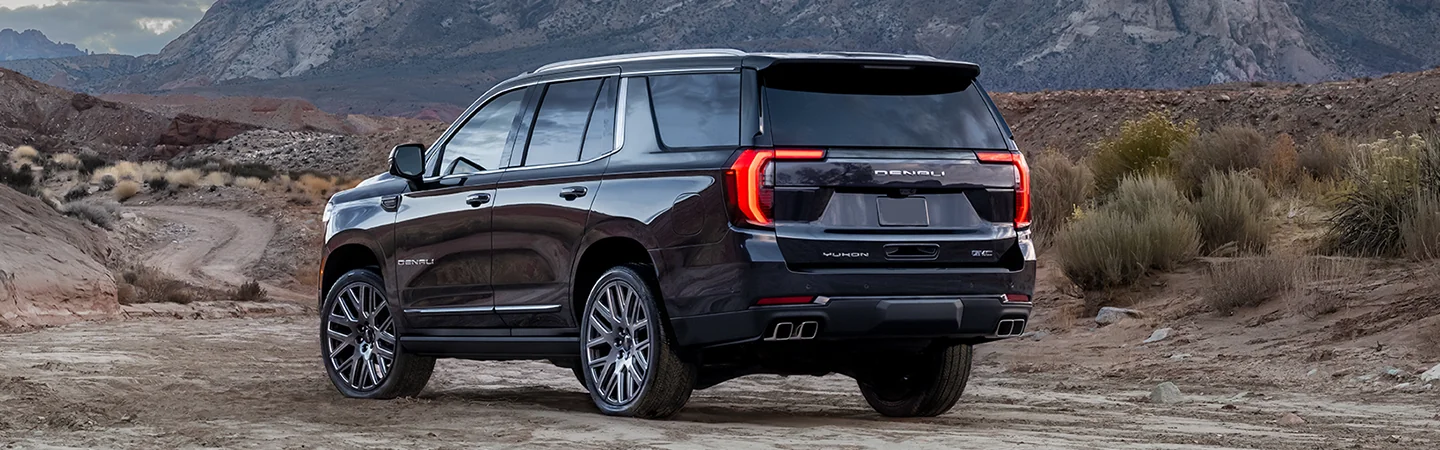 Back view of a black 2025 GMC Yukon parked in the dirt