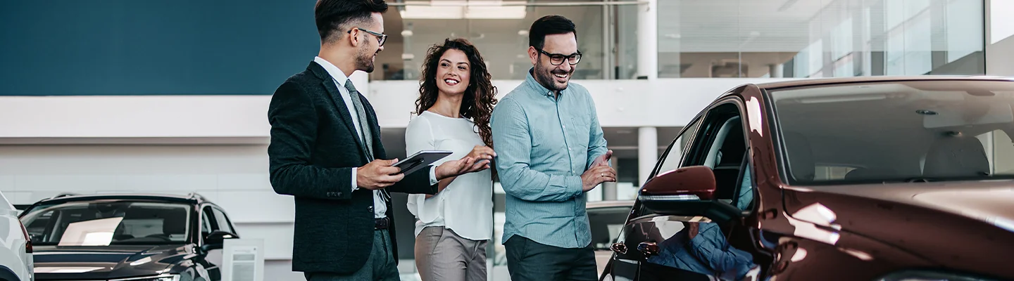 three people discussing a car purchase in dealership