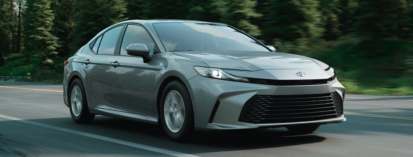 Front side view of a gray 2025 Toyota Camry driving on a road