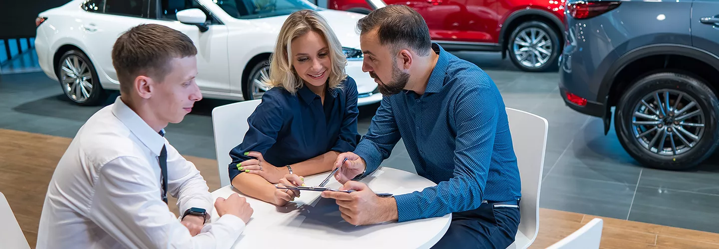 salesman taling with a husband and wife in the dealership