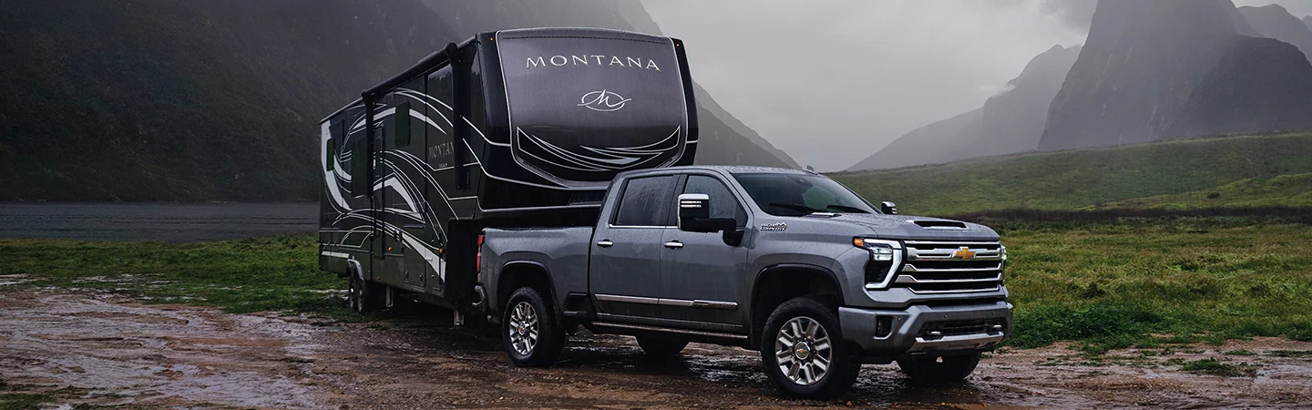 Side view of a parked gray 2026 Chevy Silverado 2500 pulling a trailer