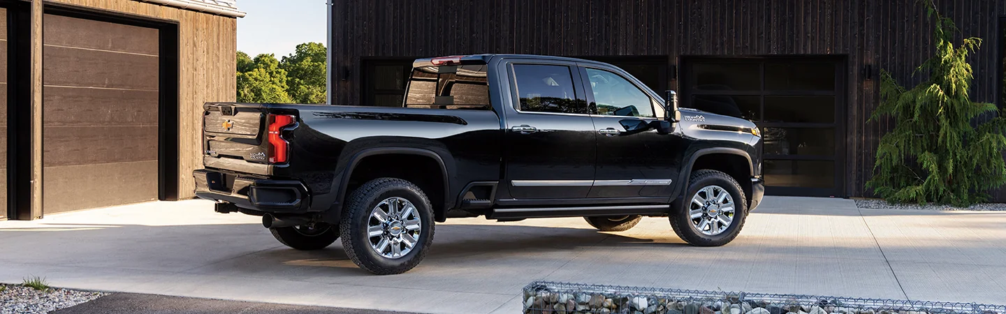 Side view of a parked black 2026 Chevy Silverado 2500 in a driveway