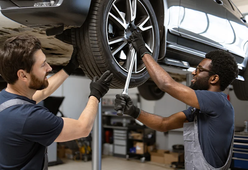 car mechanics working on car on lift