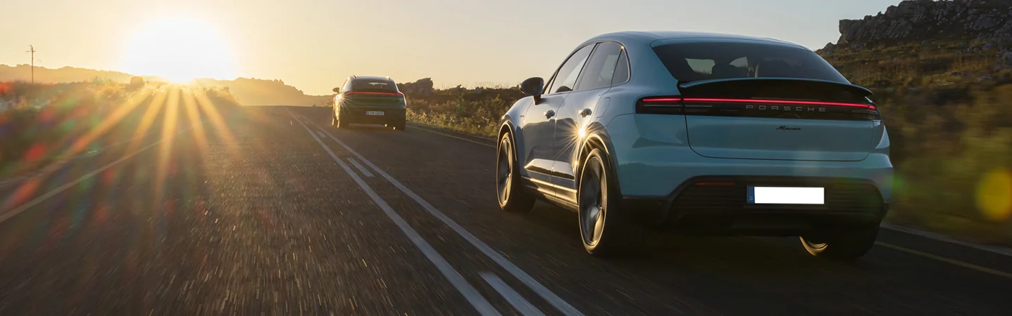 rear view of a 2025 Porsche Macan Electric driving into the sunset
