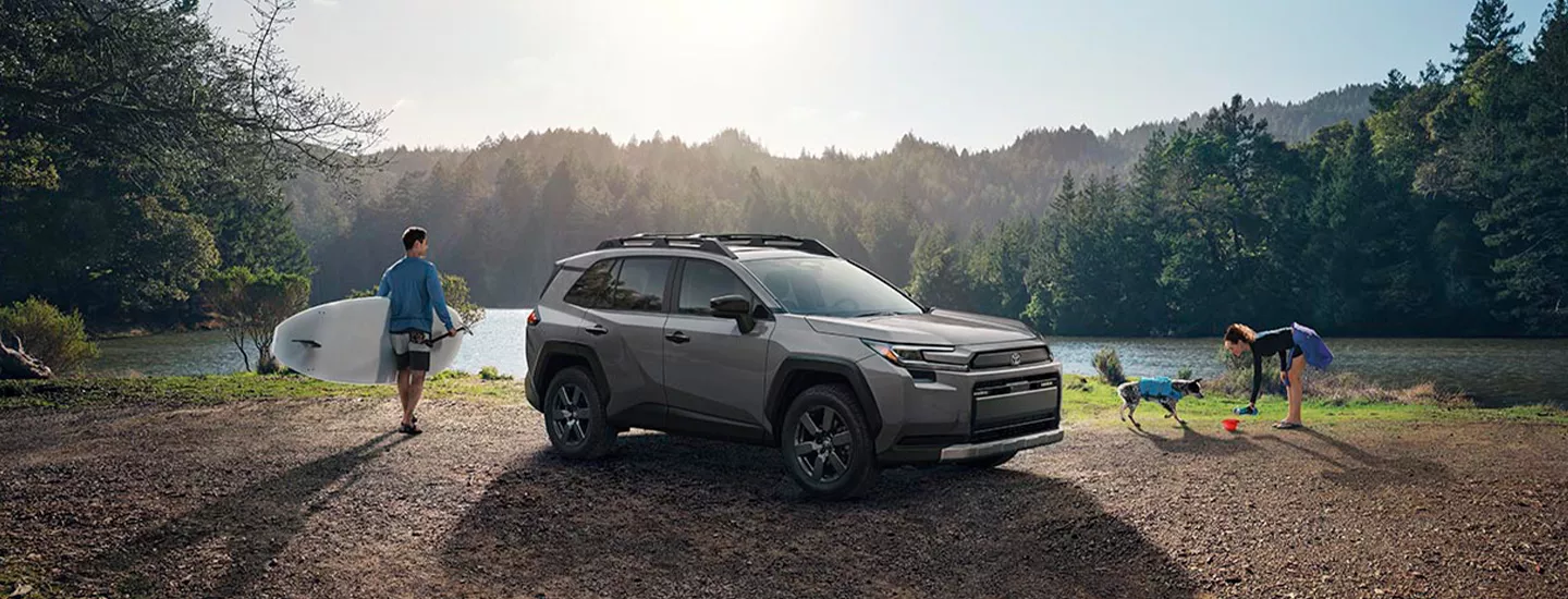 2026 Toyota RAV4 parked in fornt of a lake. A couple with thier dog outside