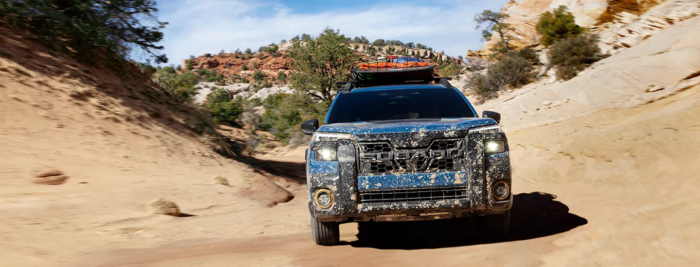 2026 Subaru Outback Wilderness driving through a dirt path with mud on the vehicle