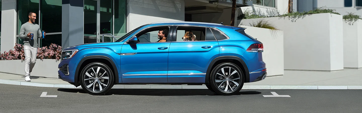 a driver side of a blue 2026 Atlas Cross Sport driving in city