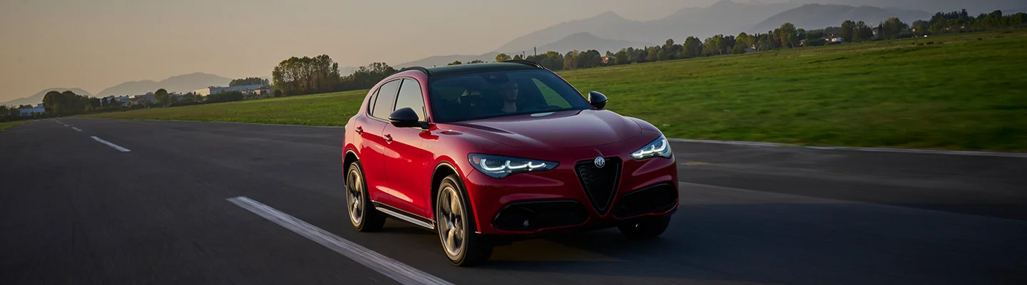 Front view of a red 2025 Alfa Romeo Stelviodrving on a road