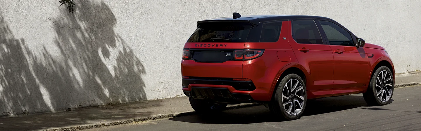 Back view of a parked red 2025 Discovery Sport on a street