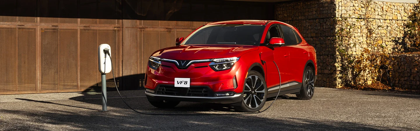 a red 2025 VinFast VF 8 Eco parked by charging station