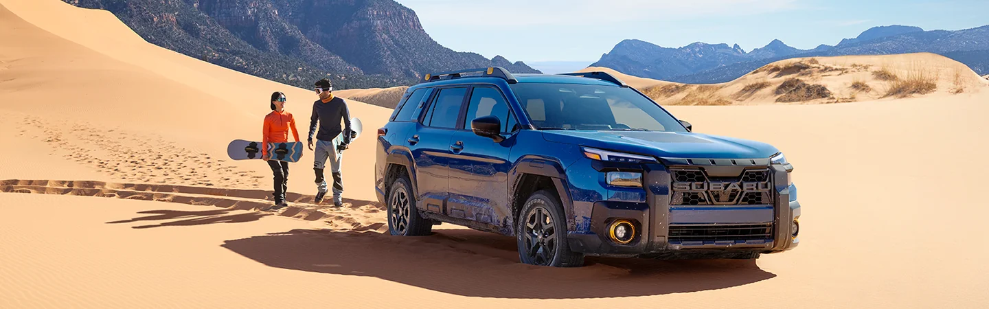2026 Subaru Outback Wilderness in a desert with sand skiers heading towards mountain of sand
