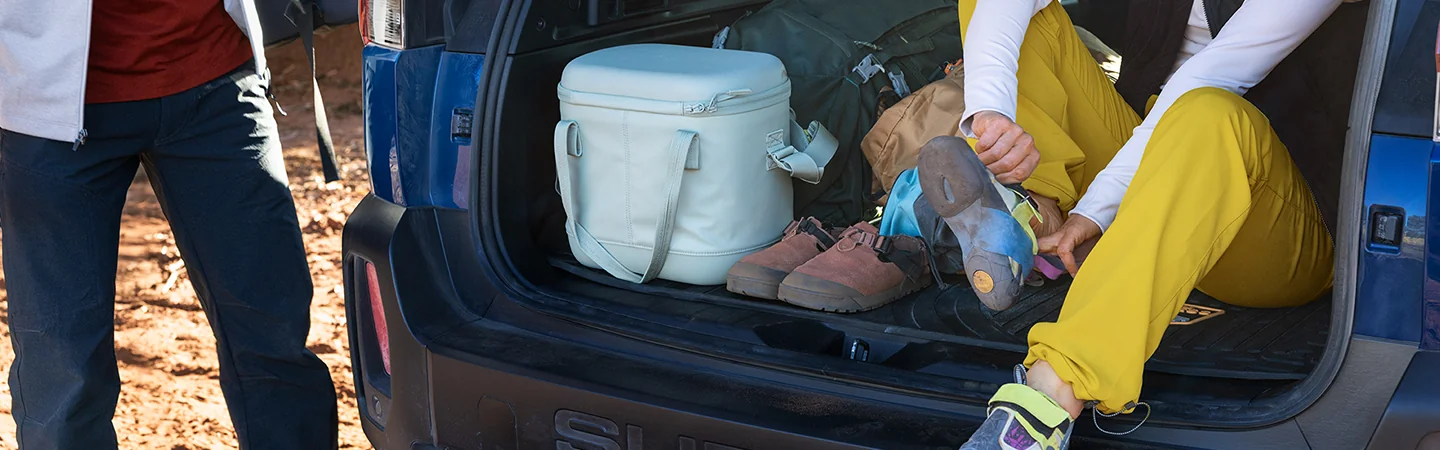 view of the hatch in back of a 2026 Subaru Outback Wilderness with a person putting on rock climbing shoes